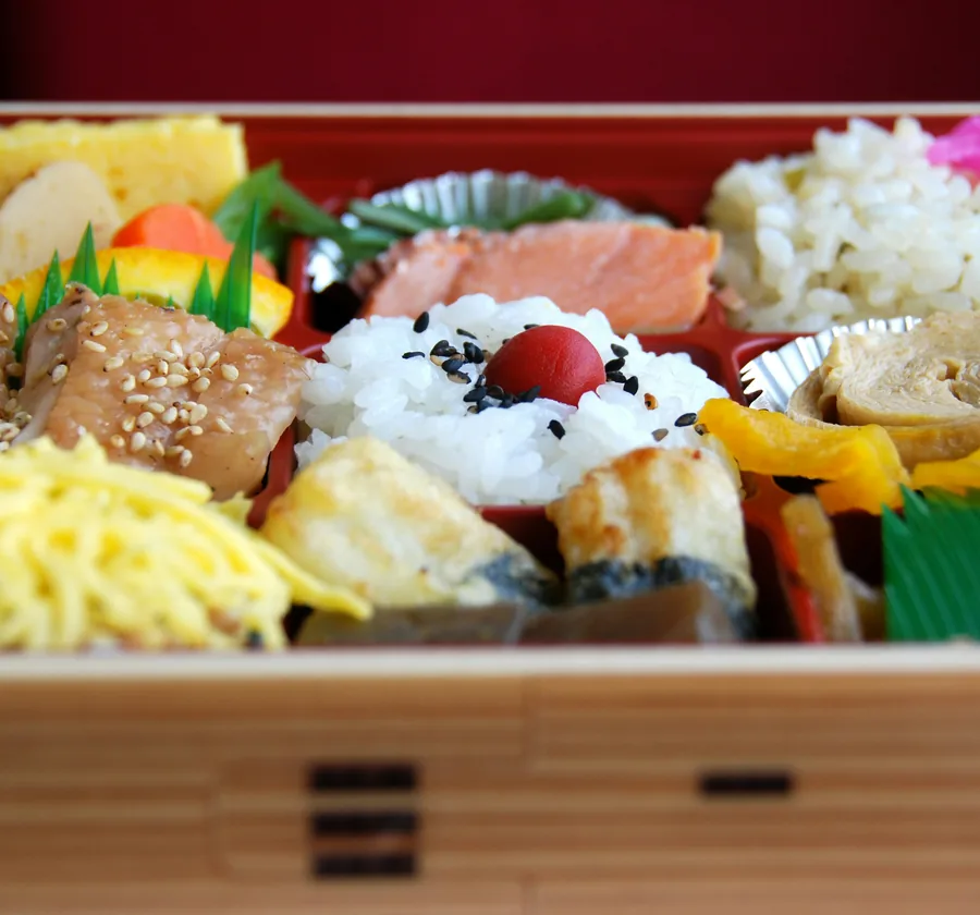 A compartmented bento box from the supermarket deli counter — grilled salmon, tamagoyaki and seasoned rice.