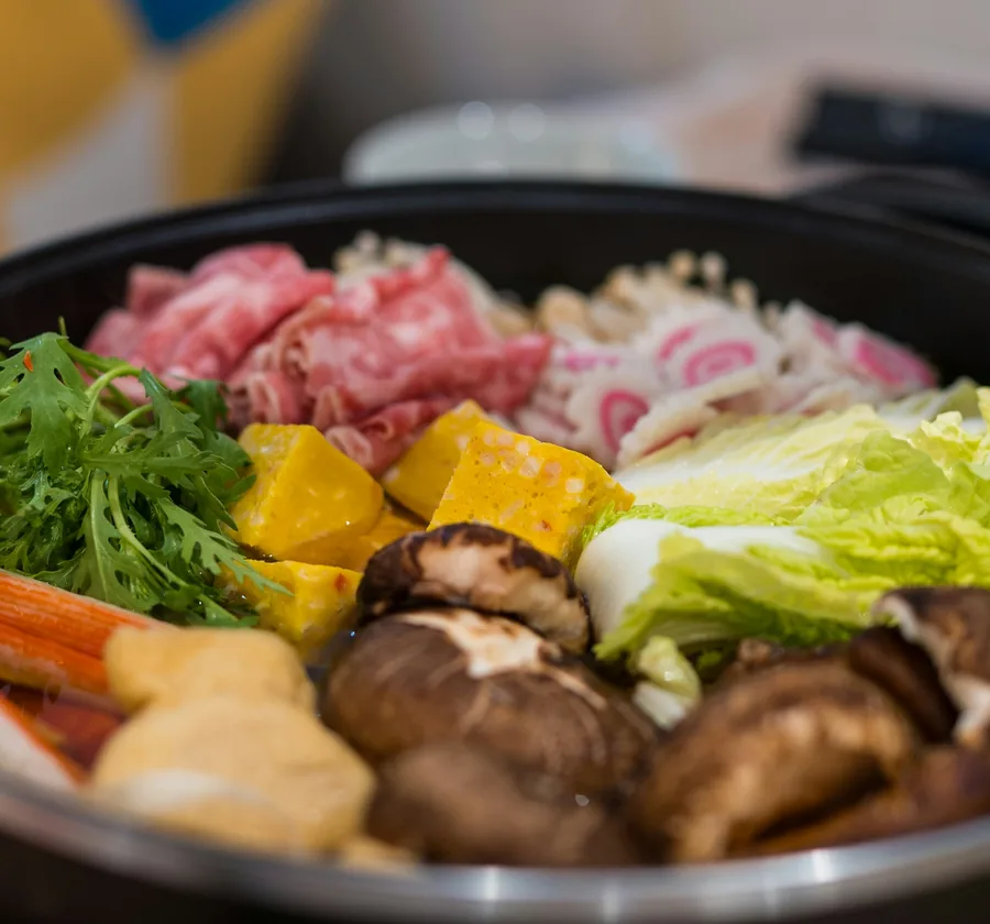 A one-pot nabe of thinly sliced beef, tofu, shiitake and greens, ready to simmer.